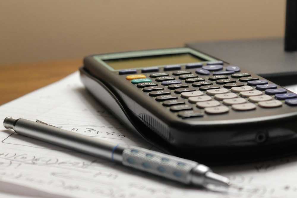 A calculator and a pen on a printed price sheet